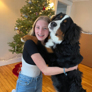Girl in scoliosis brace hugging her dog in front of christmas tree